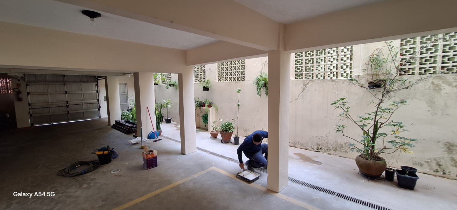 Pilares com acabamento branco e profissional realizando pintura junto ao piso