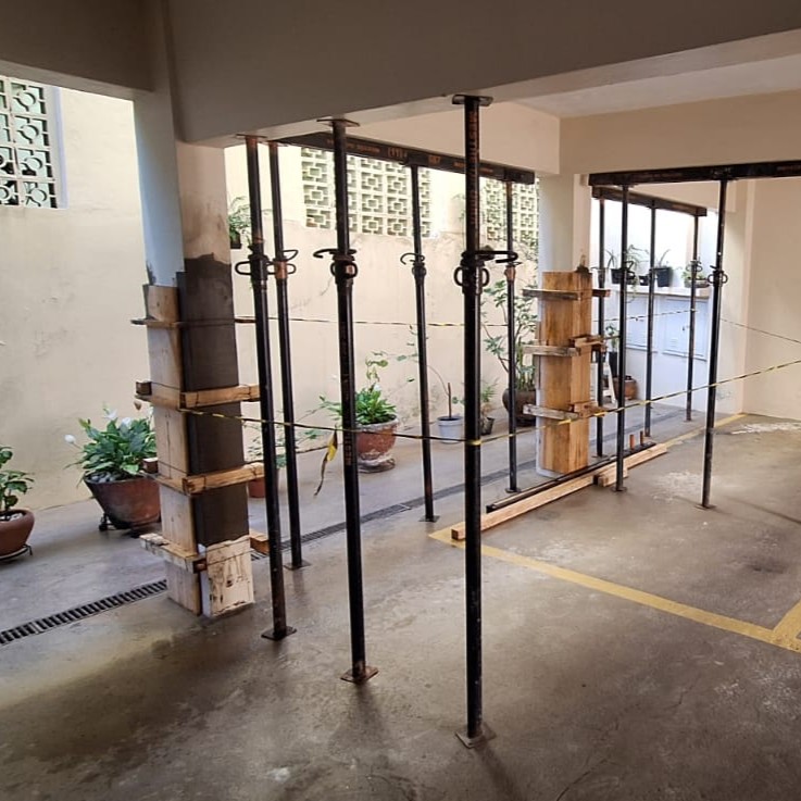 Formas de madeira ao redor dos pilares e escoras metálicas na garagem