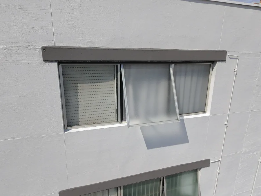 Detalhe do acabamento branco da fachada e dos contornos cinzas de uma janela