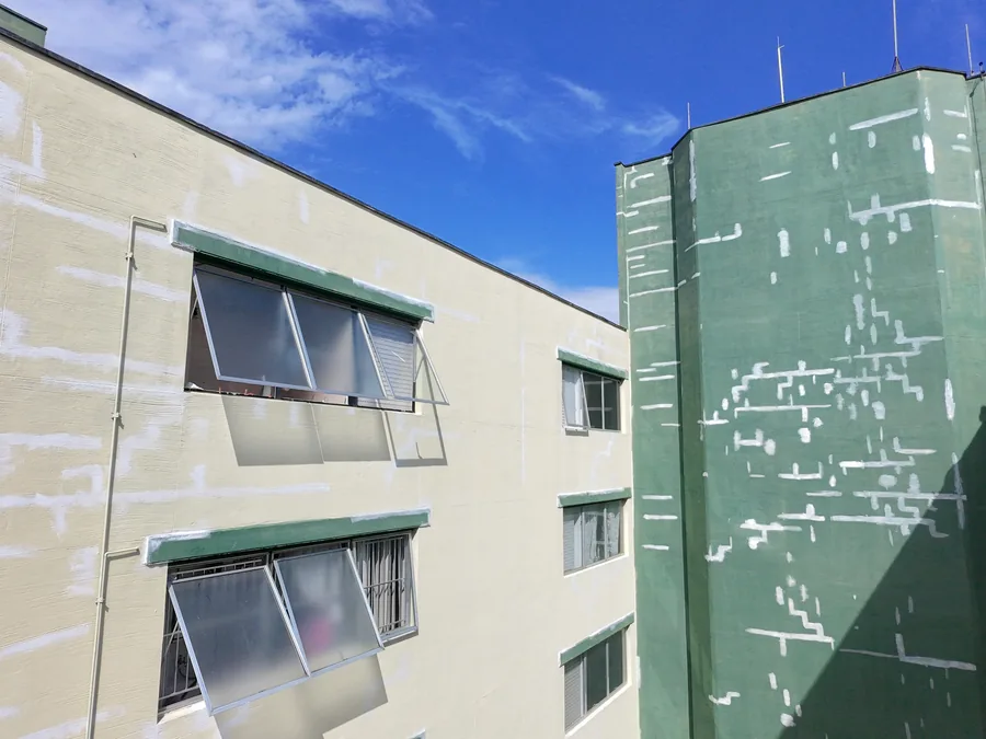 Fachada com reparos localizados visíveis sobre o revestimento antes da pintura